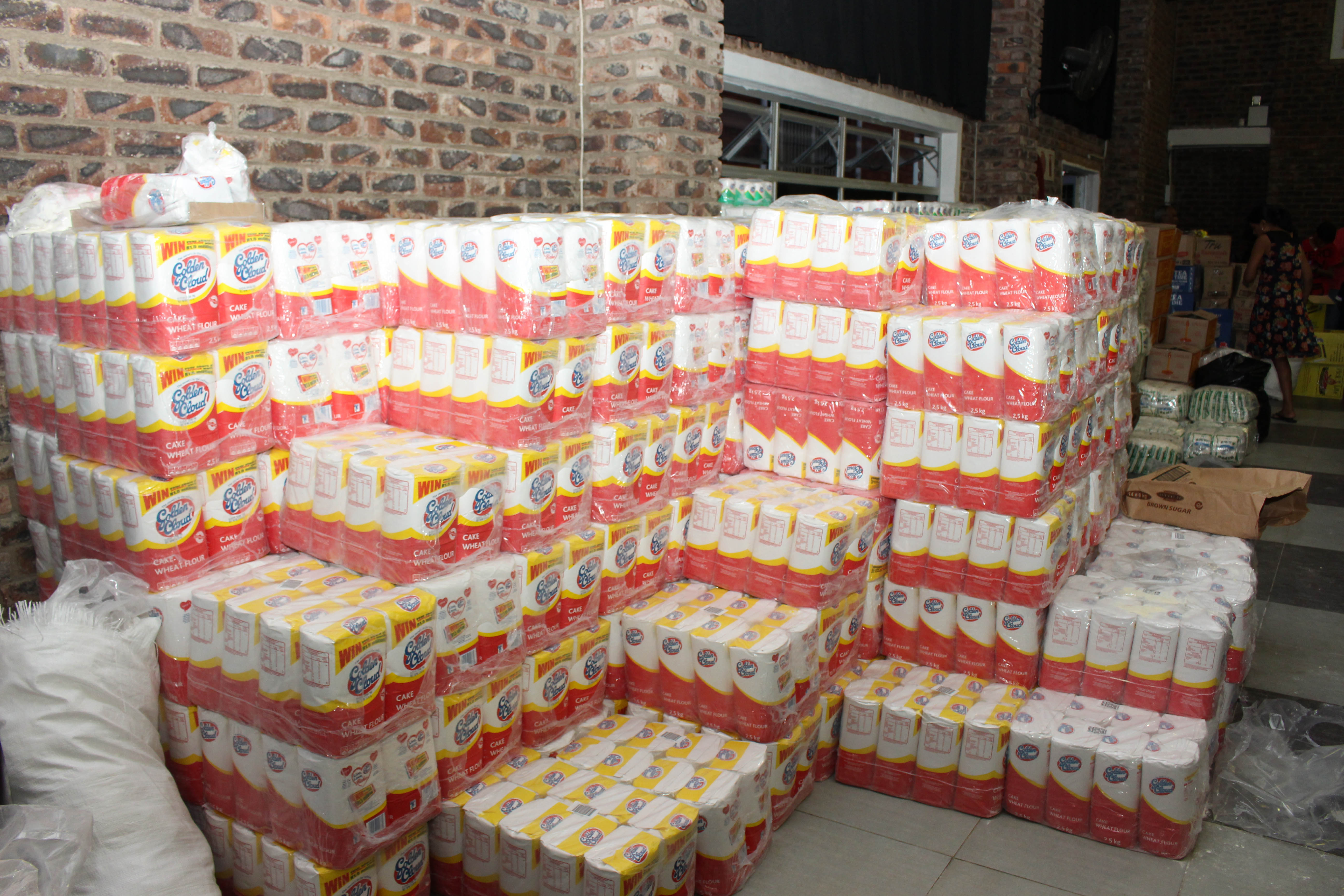 Massive pallets of Golden Cloud Cake Wheat Flour stacked high inside the Jyoti Jivanam distribution hall
